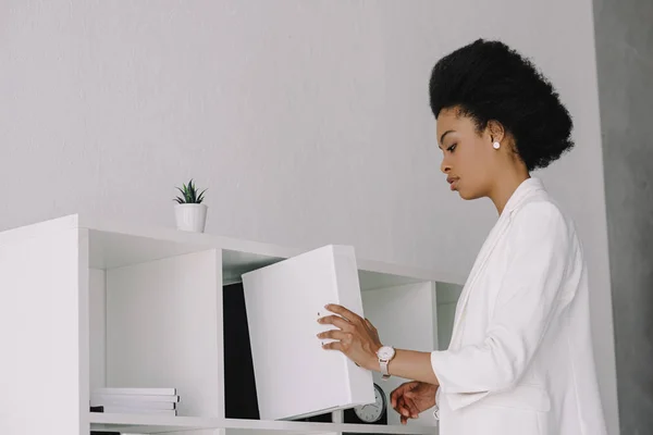 Attraktive afrikanisch-amerikanische Geschäftsfrau legt Ordner ins Regal im Büro — Stockfoto