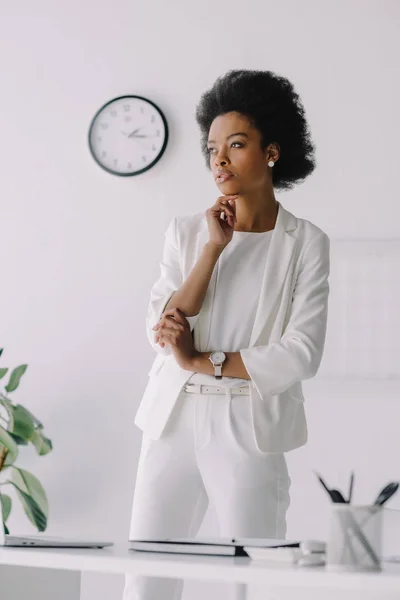 Pensativa atractiva mujer de negocios afroamericana mirando hacia otro lado en la oficina - foto de stock