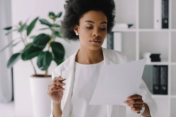 Attraente donna d'affari africana americana che legge documenti in ufficio — Foto stock