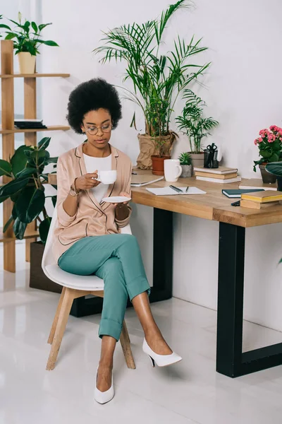 Attraente donna d'affari africana americana in possesso di una tazza di caffè in ufficio — Foto stock