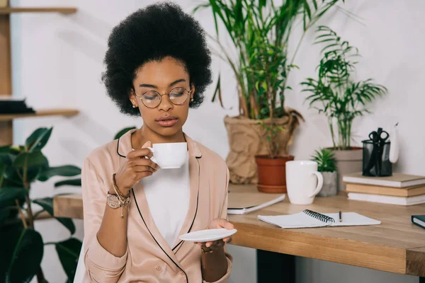 Attraktive afrikanisch-amerikanische Geschäftsfrau trinkt in der Kaffeepause Kaffee im Büro — Stockfoto