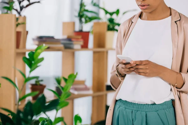 Immagine ritagliata di donna d'affari afro-americana utilizzando smartphone in ufficio — Foto stock