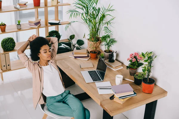 Hochwinkelige Ansicht der attraktiven afrikanisch-amerikanischen Geschäftsfrau, die auf einem Stuhl im Büro ruht — Stockfoto