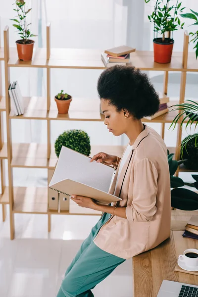 Вид збоку приваблива афроамериканська бізнес-леді читає документи в офісі — стокове фото