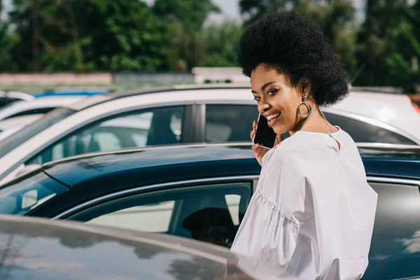 Attractive african american businesswoman talking by smartphone on parking — Stock Photo