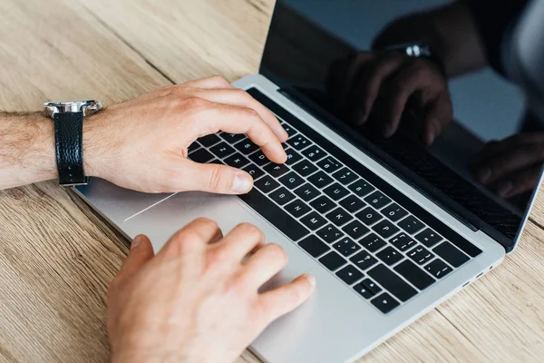 Close-up partial view of person typing on laptop with blank screen — Stock Photo