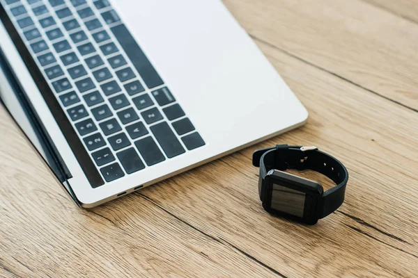 Close-up view of smartwatch and laptop on wooden table — Stock Photo