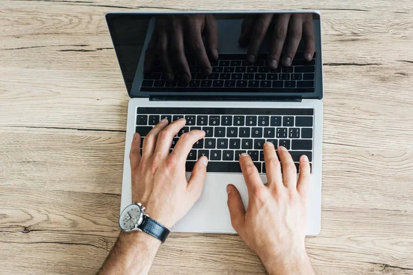 Partial top view of person using laptop with blank screen at wooden table — Stock Photo