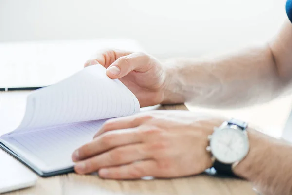 Primo piano visione parziale della persona in possesso di blocco note sul posto di lavoro — Foto stock