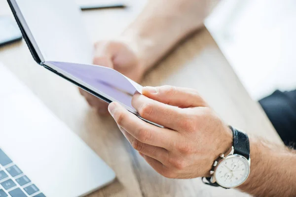 Close-up partial view of male hands holding notebook at workplace — Stock Photo