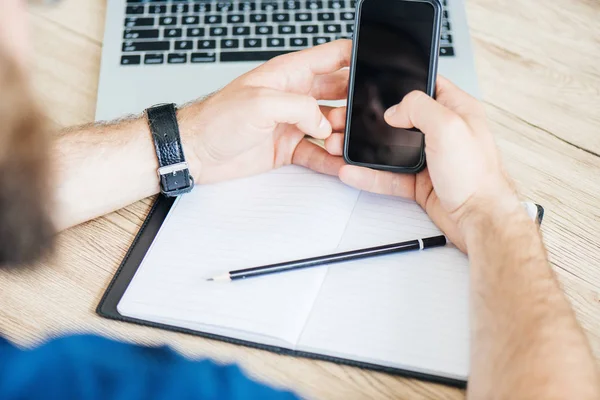 Cropped shot of person using smartphone with blank screen at workplace — Stock Photo