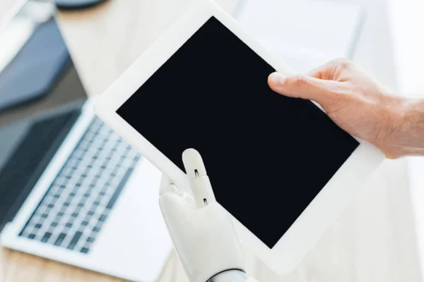 Vue rapprochée de la main humaine et du bras robotisé tenant une tablette numérique avec écran blanc — Photo de stock