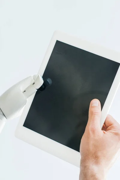 Крупним планом рука людини і роботизована рука тримає цифровий планшет з порожнім екраном ізольовано на білому — стокове фото