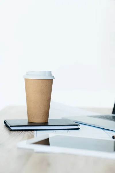 Close-up view of disposable coffee cup on notebook, laptop and digital tablet on table — Stock Photo