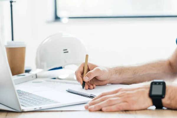 Cropped shot of person wearing smartwatch and taking notes at workplace — Stock Photo