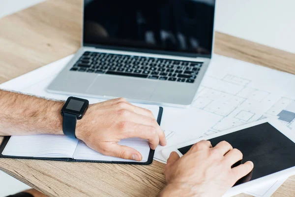 Tiro recortado de pessoa usando smartwatch e usando tablet digital no local de trabalho — Fotografia de Stock