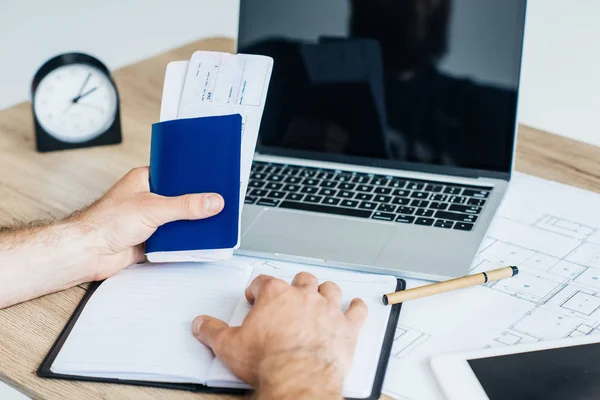 Foto recortada de la persona que tiene pasaporte con entradas en el lugar de trabajo - foto de stock