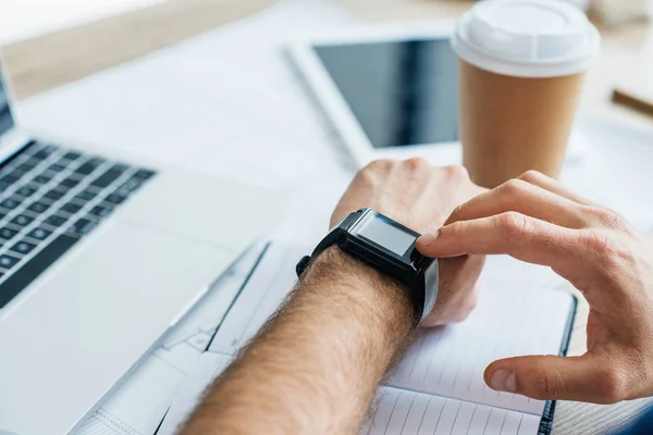 Enfoque selectivo de la persona que utiliza smartwatch en el lugar de trabajo, tiro recortado - foto de stock