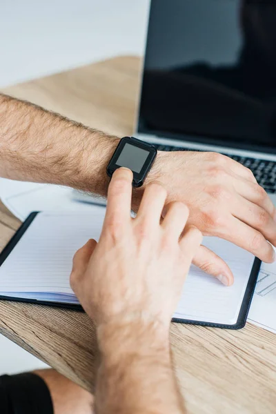 Gros plan vue partielle de la personne qui utilise smartwatch sur le lieu de travail — Photo de stock