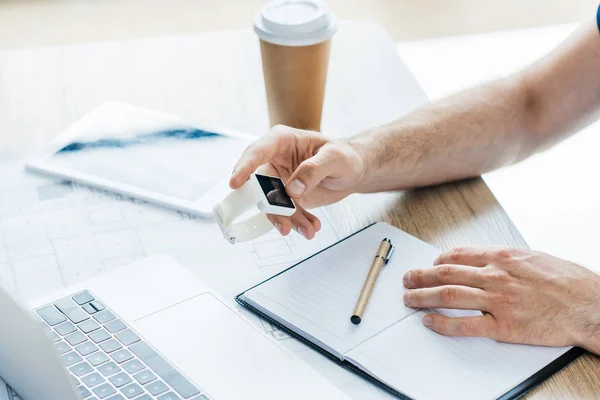 Cropped shot of person using smartwatch while sitting at workplace — Stock Photo