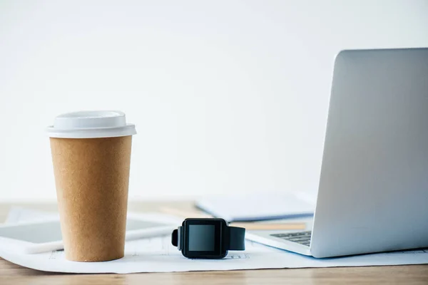 Vista de cerca de smartwatch, portátil y taza de café desechable en la mesa - foto de stock