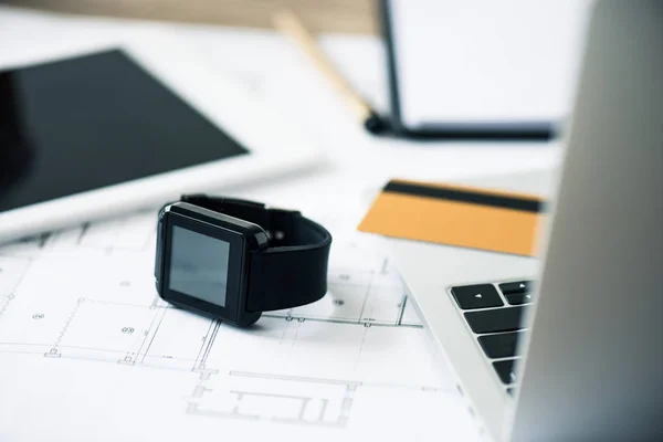 Vue rapprochée de smartwatch, ordinateur portable, tablette numérique et plan directeur sur le lieu de travail — Photo de stock