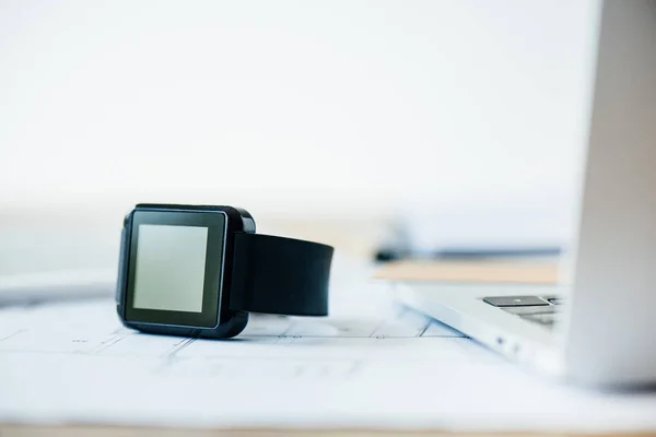 Vista ravvicinata di smartwatch e laptop sul posto di lavoro — Foto stock