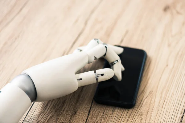 Close-up view of robot using smartphone on wooden table — Stock Photo