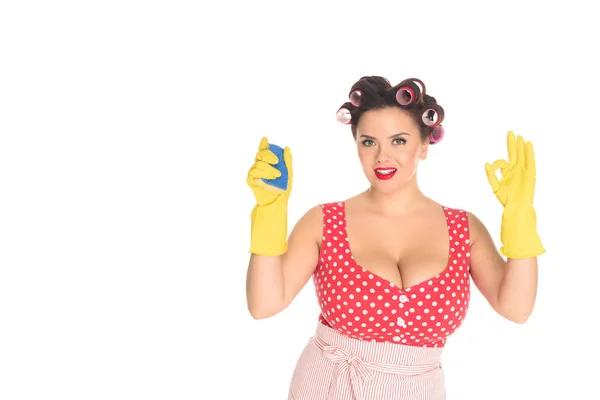 Smiling plus size woman in rubber gloves with sponge showing okay gesture isolated on white — Stock Photo