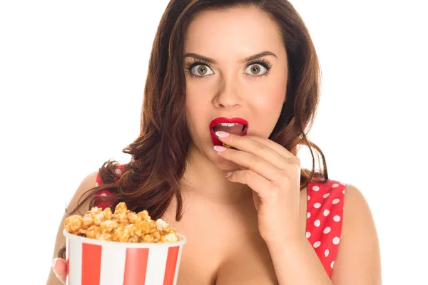 Chocado plus size mulher comer pipoca e olhando para a câmera isolada no branco — Fotografia de Stock