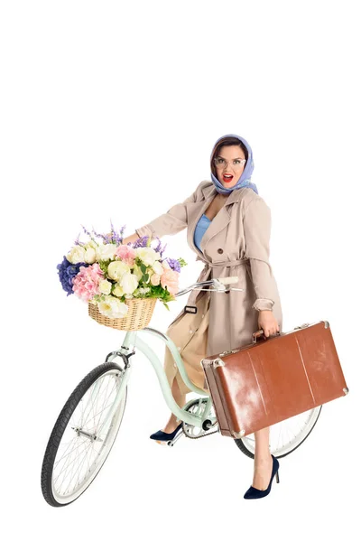 Beautiful pin up woman sitting on bicycle and holding suitcase isolated on white — Stock Photo