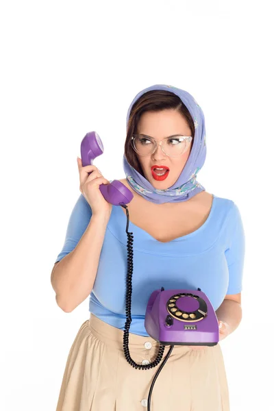 Beautiful plus size model in eyeglasses holding rotary phone and looking away isolated on white — Stock Photo