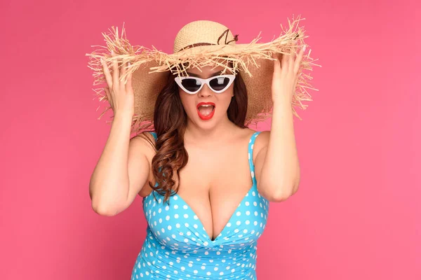 Bella giovane donna in costume da bagno con cappello di paglia e occhiali da sole isolati su rosa — Foto stock