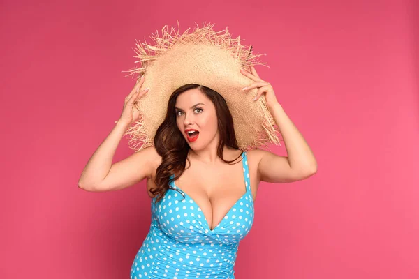 Beautiful surprised size plus woman in straw hat looking at camera isolated on pink — Stock Photo