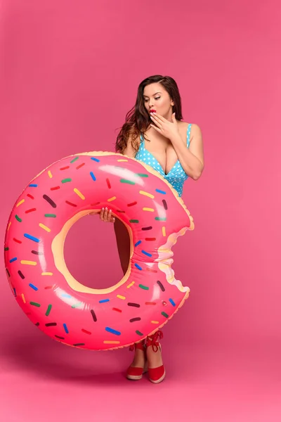 Hermosa sexy chica en traje de baño celebración inflable donut aislado en rosa - foto de stock