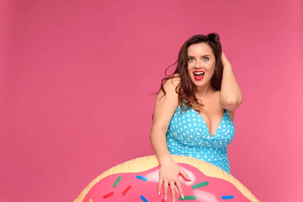 Surprised young woman in swimwear posing with inflatable ring and looking at camera isolated on pink — Stock Photo