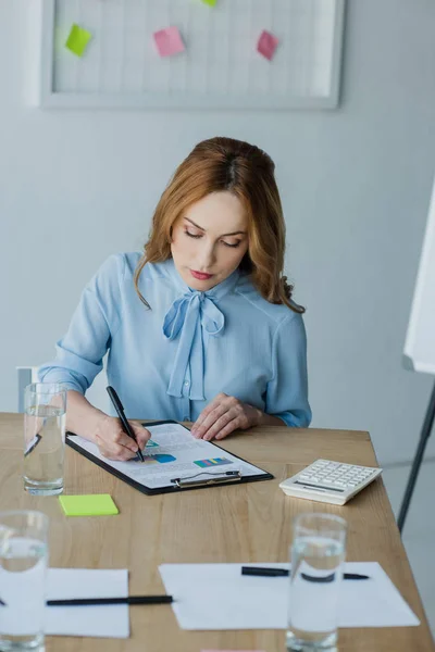 Porträt einer fokussierten Geschäftsfrau, die im Büro Papierkram erledigt — Stockfoto