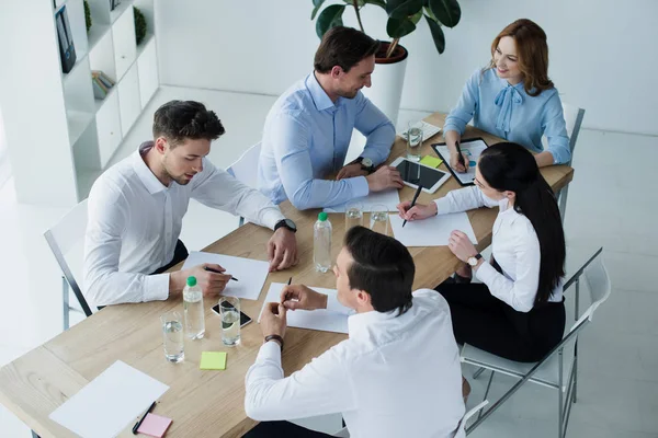 Vista ad alto angolo dei colleghi di lavoro sul posto di lavoro con documenti in ufficio — Foto stock