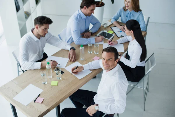 Vista de ángulo alto de los colegas de negocios en el lugar de trabajo con papeles en la oficina - foto de stock