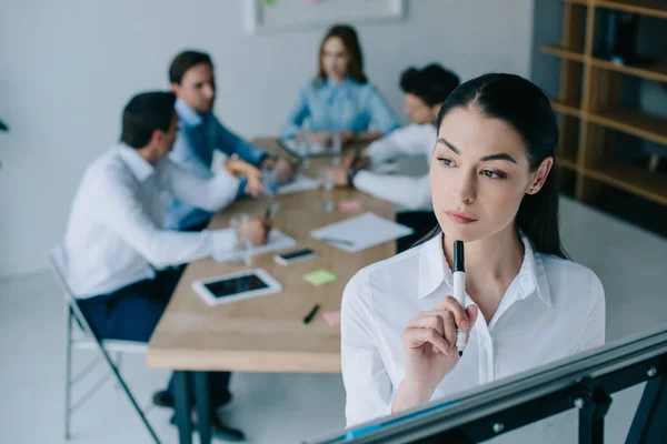Selective focus of pensive businesswoman and colleagues behind at workplace in office — Stock Photo