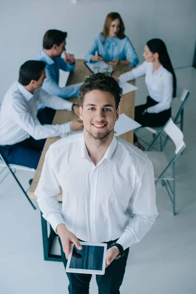 Enfoque selectivo de sonriente hombre de negocios y compañeros de trabajo en el lugar de trabajo en la oficina - foto de stock