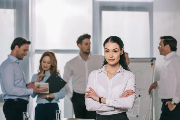 Enfoque selectivo de la mujer de negocios y colegas detrás en la pizarra blanca en la oficina - foto de stock