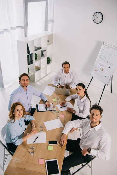 Vista de ángulo alto de los colegas de negocios sonrientes en el lugar de trabajo en la oficina - foto de stock