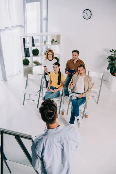 Vue partielle des gens d'affaires à l'écoute du mentor pendant la formation en entreprise au bureau — Photo de stock