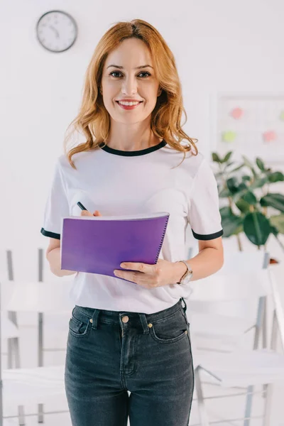 Portrait of smiling businesswoman in casual clothing with notebook in hands, business training concept — Stock Photo