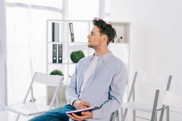 Geschäftsmann in lässiger Kleidung mit Notizbuch auf Bürostuhl sitzend, Businessschulungskonzept — Stockfoto