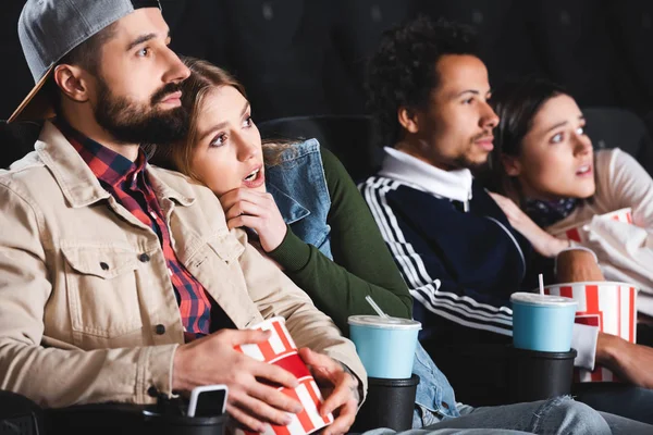 Enfoque selectivo de amigos multiculturales asustados viendo películas en el cine - foto de stock