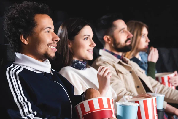 Selektiver Fokus eines afrikanisch-amerikanischen Mannes, der mit Freunden im Kino einen Film anschaut — Stockfoto