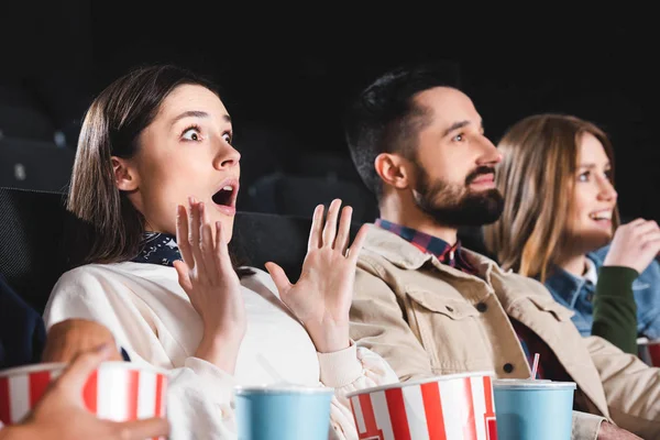 Foyer sélectif de femme choquée regarder un film avec des amis au cinéma — Photo de stock