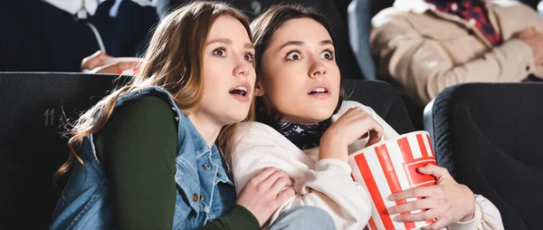 Panoramaaufnahme verängstigter Freunde beim Popcorn-Gucken im Kino — Stockfoto